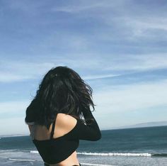 a woman standing on top of a beach next to the ocean