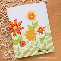 a close up of a card on a table with lace doily and flowers in the background