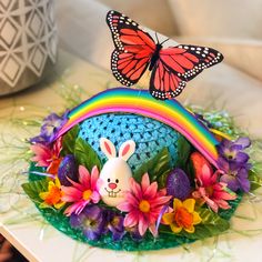 a colorful hat with a butterfly on top and flowers around the bottom, sitting on a table