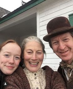 three people are posing for a photo in front of a house