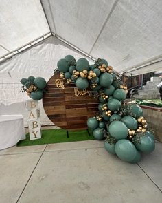 balloons and greenery decorate the entrance to a baby's first birthday party in a tent