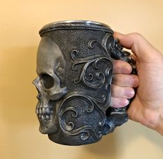 a person holding a skull shaped mug in their hand