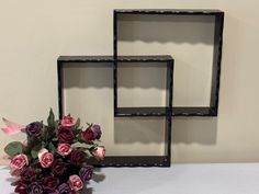 three black frames with pink and purple flowers in front of them on a white table