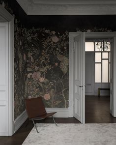 an empty room with a chair and wallpaper