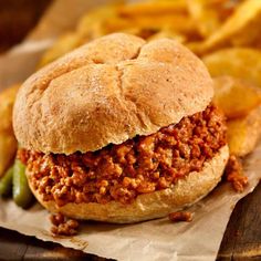 a sloppy joe sandwich with pickles and french fries on the side, ready to be eaten