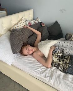 a young child is laying on a bed with pillows