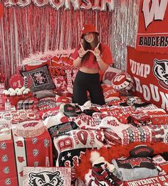 a woman standing in front of a pile of red and white football themed merchandise items