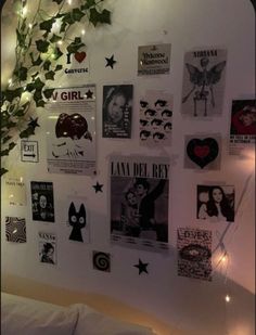 a bedroom wall covered in posters and lights with ivy growing up the side of it