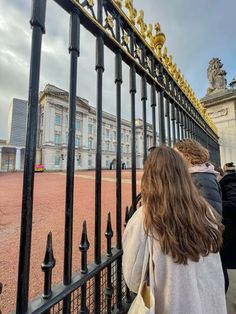 people are walking up and down the stairs in front of a fence with gold letters on it