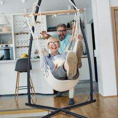 a man and woman sitting in a hammock with their feet on the ground