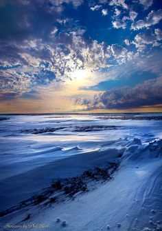 the sun shines brightly through clouds over an icy beach