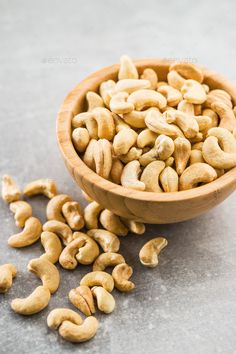 a wooden bowl filled with cashews on top of a gray surface - stock photo - images