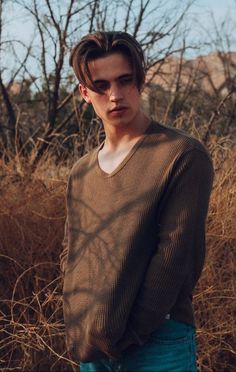 a young man standing in the middle of a field with his hands on his hips