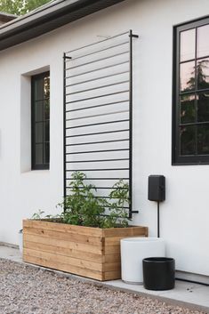 a planter with plants in it next to a white building