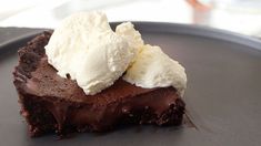 a piece of chocolate cake with ice cream on top is sitting on a black plate