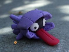 an odd looking purple toy with a red object sticking out of it's mouth