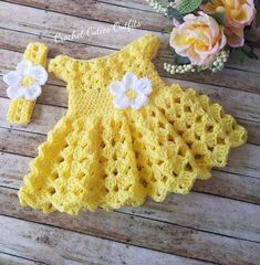 a crocheted yellow dress with white flowers on it and a flower headband