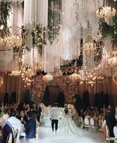 a bride and groom walking down the aisle at their wedding ceremony in front of an elaborate chandelier