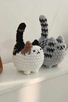 three crocheted cats sitting on top of a white shelf next to each other