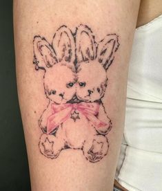 a woman's arm with a tattoo of two rabbits holding each other on it