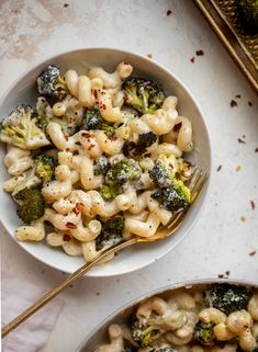 two bowls filled with macaroni and broccoli on top of a table