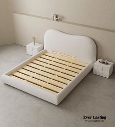 a white bed with wooden slats on the bottom and headboard is next to two nightstands