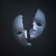 two people wearing masks in the dark with one person's face partially hidden behind them