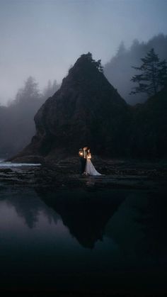 a bride and groom standing in the water at night