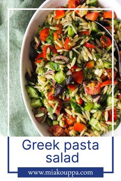 greek pasta salad in a white bowl on a green tablecloth with a blue border