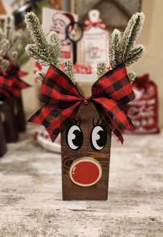 a wooden reindeer head with red nose and plaid bow sitting on top of a table