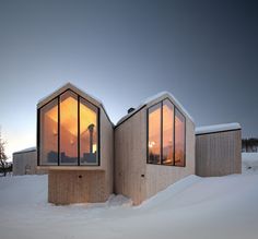 two buildings are covered in snow with windows on each side and one is lit up by the sun