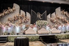 an elaborately decorated stage set up for a wedding ceremony with floral arrangements and monogrammed chairs