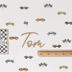 a wall with cars on it and the word tom spelled in wooden letters