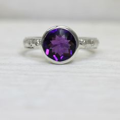 This amethyst ring is such a simple, yet dazzling piece. Though the art deco band and protective tapered bezel stone setting make for a lovely ring, the real show stopper here is the deep amethyst stone, which has vibrant internal fire and a faceted top that enhances its sparkle even further.  This stone is a generous 9mm, and it is well protected by its setting which envelops it on all sides.  I do have other stones available, too, so let me know if you're interested in a quote for something el Heirloom Solitaire Purple Amethyst Ring, Heirloom Amethyst Solitaire Ring, Classic Amethyst Birthstone Ring With Accent Stones, Classic Purple Amethyst Ring Round Cut, Classic Purple Amethyst Round Cut Ring, Classic Purple Round Band Ring, Classic Purple Amethyst Ring With Round Cut, Classic Amethyst Ring With Round Cut, Classic Amethyst Round Band Ring