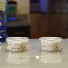 two plastic cups with sprinkles are sitting on a counter