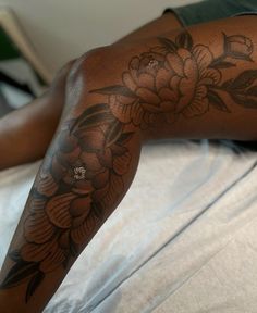 a person laying on a bed with a flower tattoo on their arm and leg,