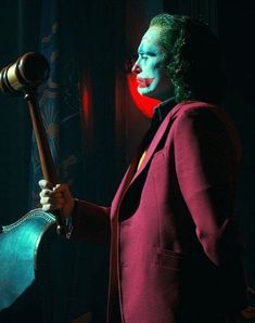 a man dressed as the joker holding a large wooden mallet in his right hand