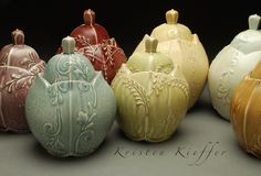 several different colored vases sitting next to each other on a gray surface with black background