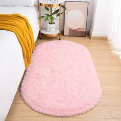 a pink rug is on the floor next to a white bed and yellow throw blanket