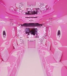 the inside of a pink and white bus with lights on it's walls, couches and mirrors