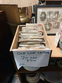 old love letters are stacked in a wooden box on a table next to a lamp