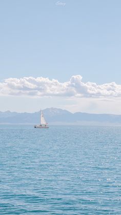 a sailboat in the ocean with mountains in the background