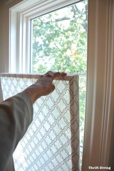 a person is holding up a window screen