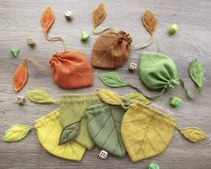 four different colored leaves and two dice bags on a wooden surface with buttons in the middle