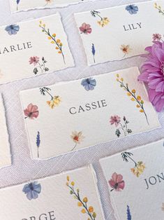 four place cards with flowers on them and the name of each card is shown next to a purple flower