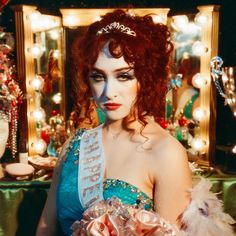 a woman with red hair wearing a tiara in front of a mirror and christmas decorations