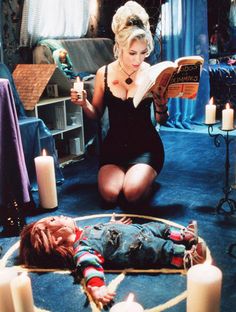 a woman sitting on the floor in front of candles and a dead body laying on the floor