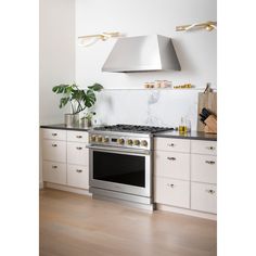 a stove top oven sitting inside of a kitchen next to white cupboards and drawers