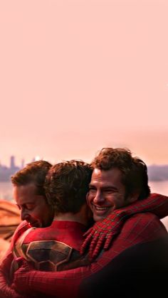 two men hugging each other in front of the ocean