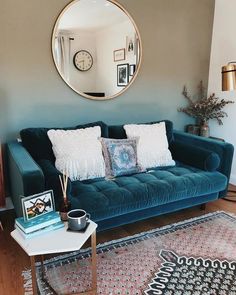 a living room filled with furniture and a large round mirror on the wall above it